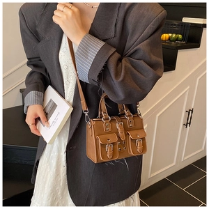 Detailed view of a brown vintage satchel bag with multiple pockets and metal buckles