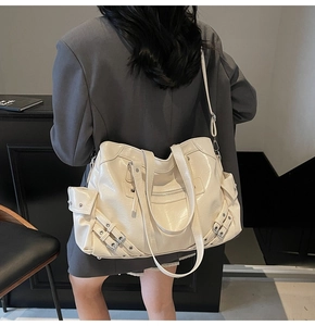 Detail view of large cream-white leather tote bag with functional pockets and metal buckles