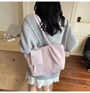 Sac cabas en daim rose avec pochette assortie porté à l'épaule dans un bureau à domicile