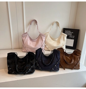 Five assorted large denim and suede hobo tote bags displayed on marble display tiers