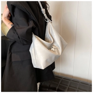 Close-up of metallic hobo bag with silver butterfly pendant and knot shoulder strap detail