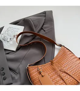 Detail of brown woven texture handbag with matching leather shoulder strap and square tag