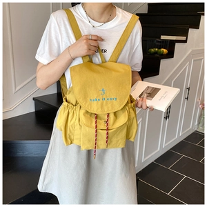 Detail of yellow canvas backpack with take it easy embroidery and red pattern drawstring