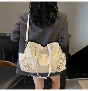 Modèle portant un grand sac cabas crème à rivets avec poches et bandoulière