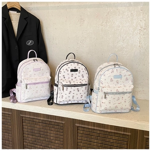 Détail de sacs à dos à motifs de dessins animés en violet, noir et bleu avec poches zippées
