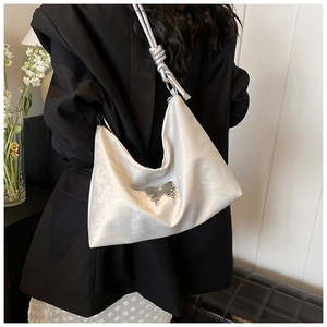 Detail of white hobo bag with pearl luster finish and silver butterfly pendant