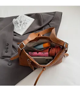 Interior view showing the large capacity of the brown woven shoulder bag with items