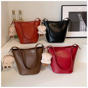 Detail of four colorful bucket bags in PU leather with cute plush toast charms on display