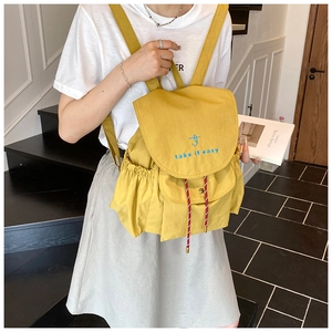 Détail d'un sac à dos jaune avec rabat à cordon et broderie take it easy pour femmes