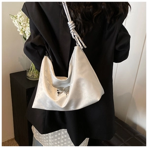 Detail of silver tote bag with metallic butterfly clasp and twisted shoulder strap