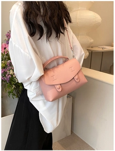 Dettaglio della borsa a tracolla rosa in pelle martellata indossata con camicia bianca