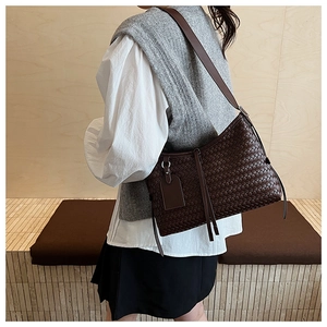 Detailed view of dark brown woven leather pattern and adjustable strap on the bucket bag