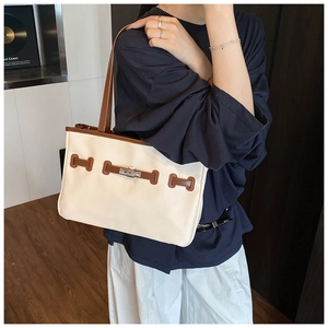 Detail of contrast stitching and metal turn-lock on the cream and brown leather tote bag
