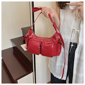 Detailed view of glossy red shoulder bag with multiple functional zipper pockets