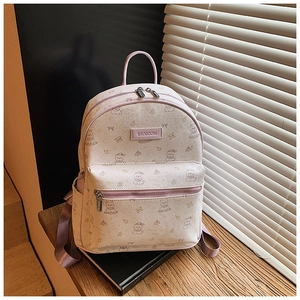 Détail d'un sac à dos crème avec imprimés d'ours violets et logo sur une table en bois
