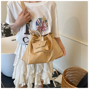 Sac fourre-tout en cuir plissé beige avec pochette porté par un mannequin chic