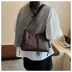 Detail of dark brown woven shoulder bag showing leather texture and adjustable strap