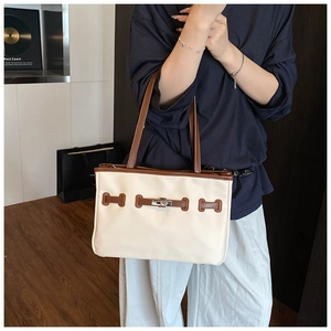 Detail view of large contrast stitching canvas tote bag with metal twist lock and leather trim