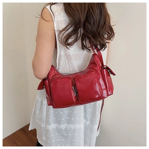 Detail of red patent leather shoulder bag with multiple zippers and glossy finish