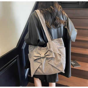 Canvas tote bag with large bow and white star patterns shown on a model's shoulder