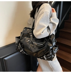 Close-up of black wrinkled leather bag with silver rivets and biker-style buckles