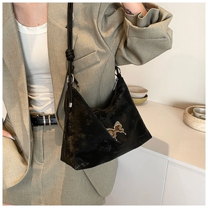 Detail of black velvet tote bag with silver bow charm and rope shoulder strap