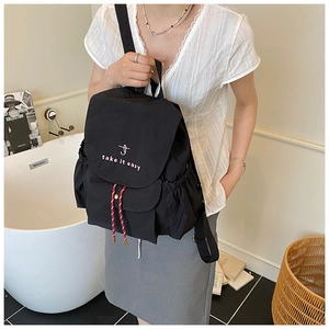 Detail of black canvas backpack with white take it easy embroidery and red drawstring