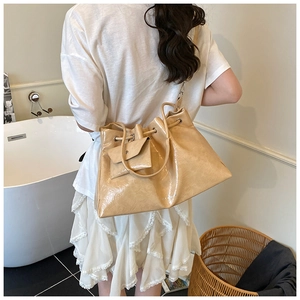 Détail du sac seau plissé beige avec texture brillante et petit porte-monnaie