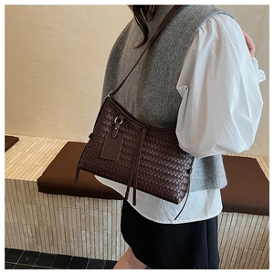 Detail of dark brown woven shoulder bag shown on model for size and fit reference