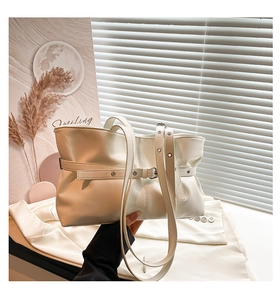 Détail d'un sac à bandoulière en similicuir crème avec boucles et plis latéraux doux