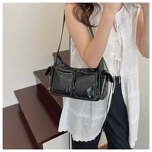 Detail of black glossy PU leather shoulder bag with functional dual zipper front pockets