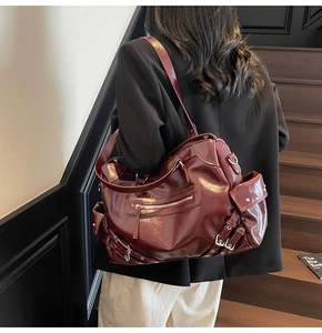 Detail of burgundy glossy oil-wax leather tote bag with metal zippers and side buckle