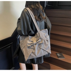 Detail of grey shoulder tote bag with silver star prints and large bow decoration