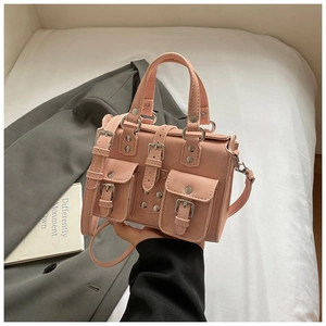Detail view of pink multi-pocket handbag with silver metal buckles and matte texture