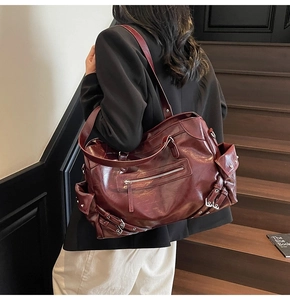 Détail d'un sac cabas bordeaux style motard avec boucles argentées et rivets