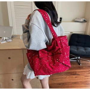 Detailed view of red bow tote bag with star pattern on canvas texture shown in lifestyle setting