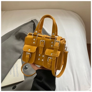 Macro shot of bright yellow multi-pocket tote bag with metal buckles and leather texture
