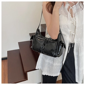 Detail of glossy black shoulder bag with multiple functional silver zipper pockets