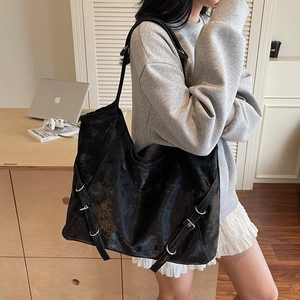 Chic black oversized shoulder bag in distressed faux leather with decorative metal buckles