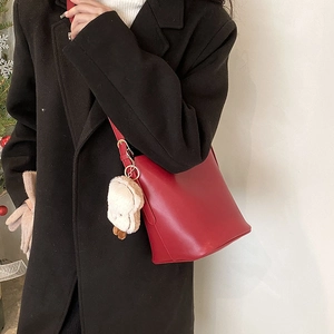 Minimalist red bucket bag for women with plush animal charm in a winter festive scene