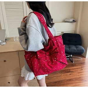 Red canvas tote bag featuring white star prints and a large bow detail shown on shoulder