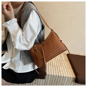 Detailed close-up of brown woven leather hobo bag with matching shoulder strap and hangtag