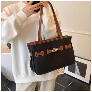 Detail of minimalist canvas tote with contrast leather trim and classic buckle closure