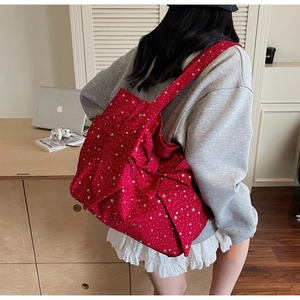 Close-up of red star-patterned canvas tote bag with large bow detail worn on shoulder
