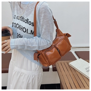 Detail of caramel vintage shoulder bag showing multiple zipper pockets and glossy texture