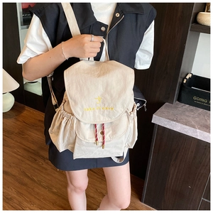 Détail du sac à dos crème avec broderie 'take it easy' et fermeture par cordon de serrage