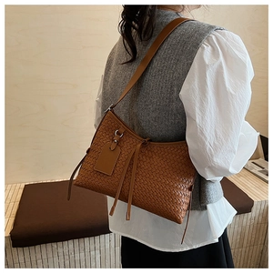 Macro detail of the brown intrecciato woven texture on a stylish leather shoulder bag