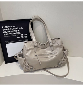 Detail view of large beige PU leather tote bag with silver studs and zipper accents
