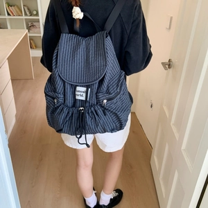 Minimalist navy plaid drawstring backpack with side zip pockets shown on model