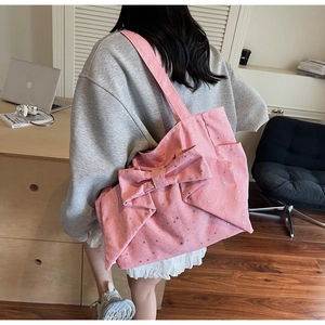 Pink canvas tote bag with silver star prints and a large bow shown in lifestyle setting